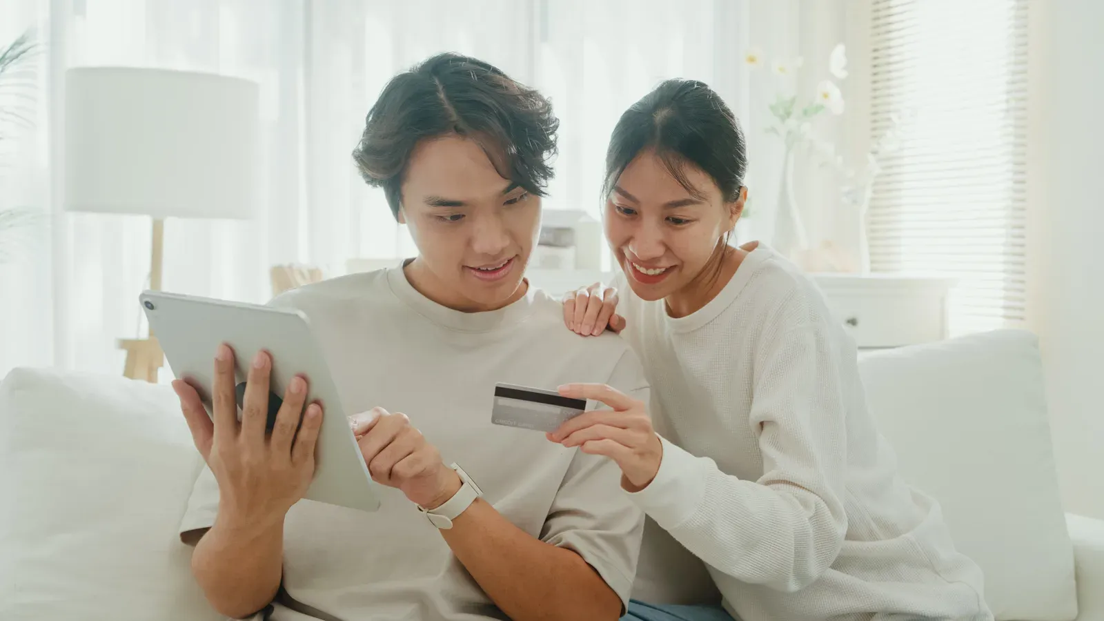Couple at home using a tablet and credit card to make an online payment