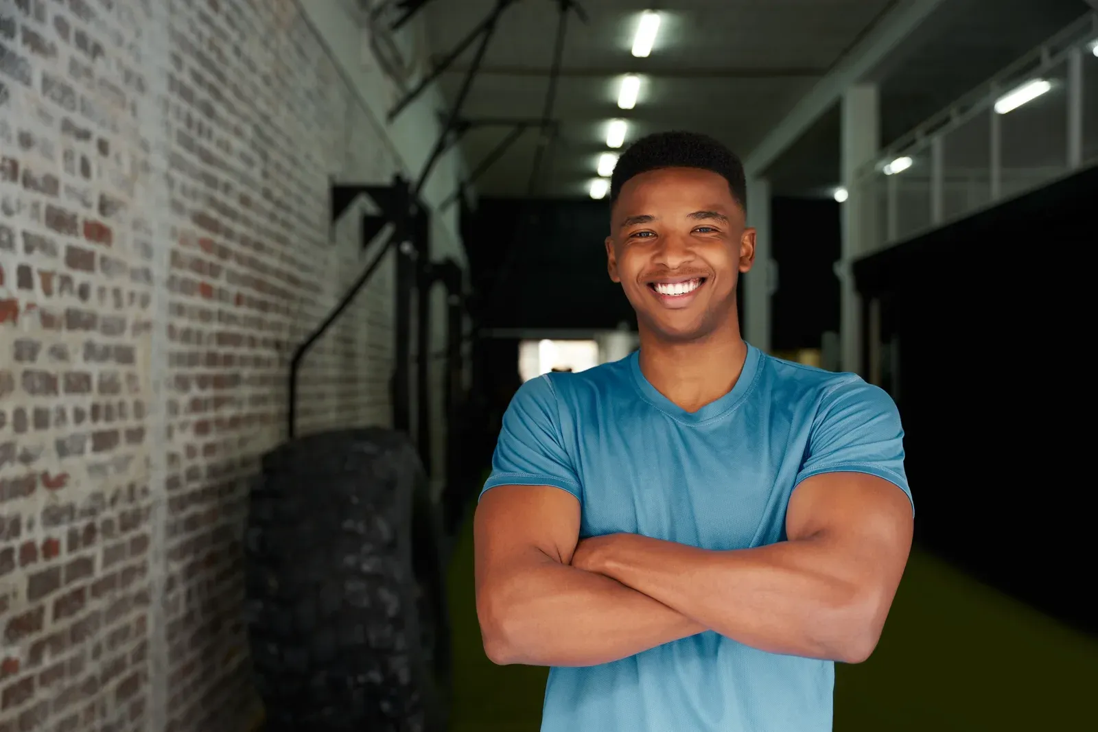 Confident personal trainer standing with crossed arms on the gym floor