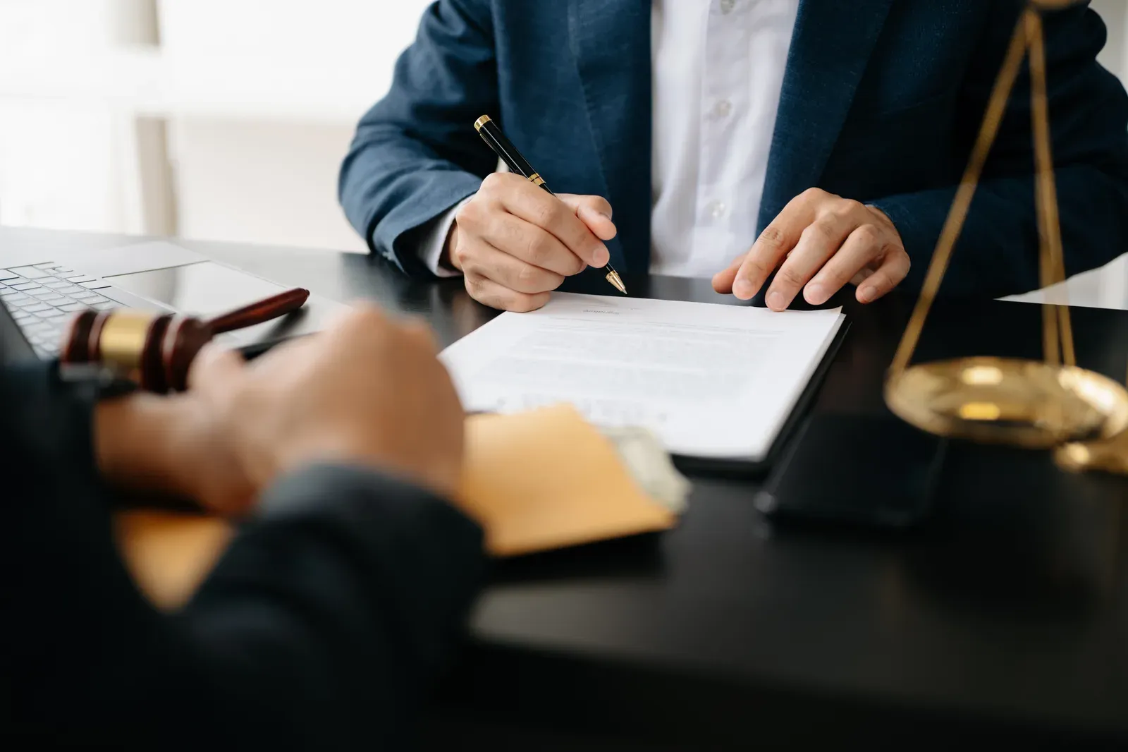 Two professionals going over contract pages at a desk with a gavel nearby