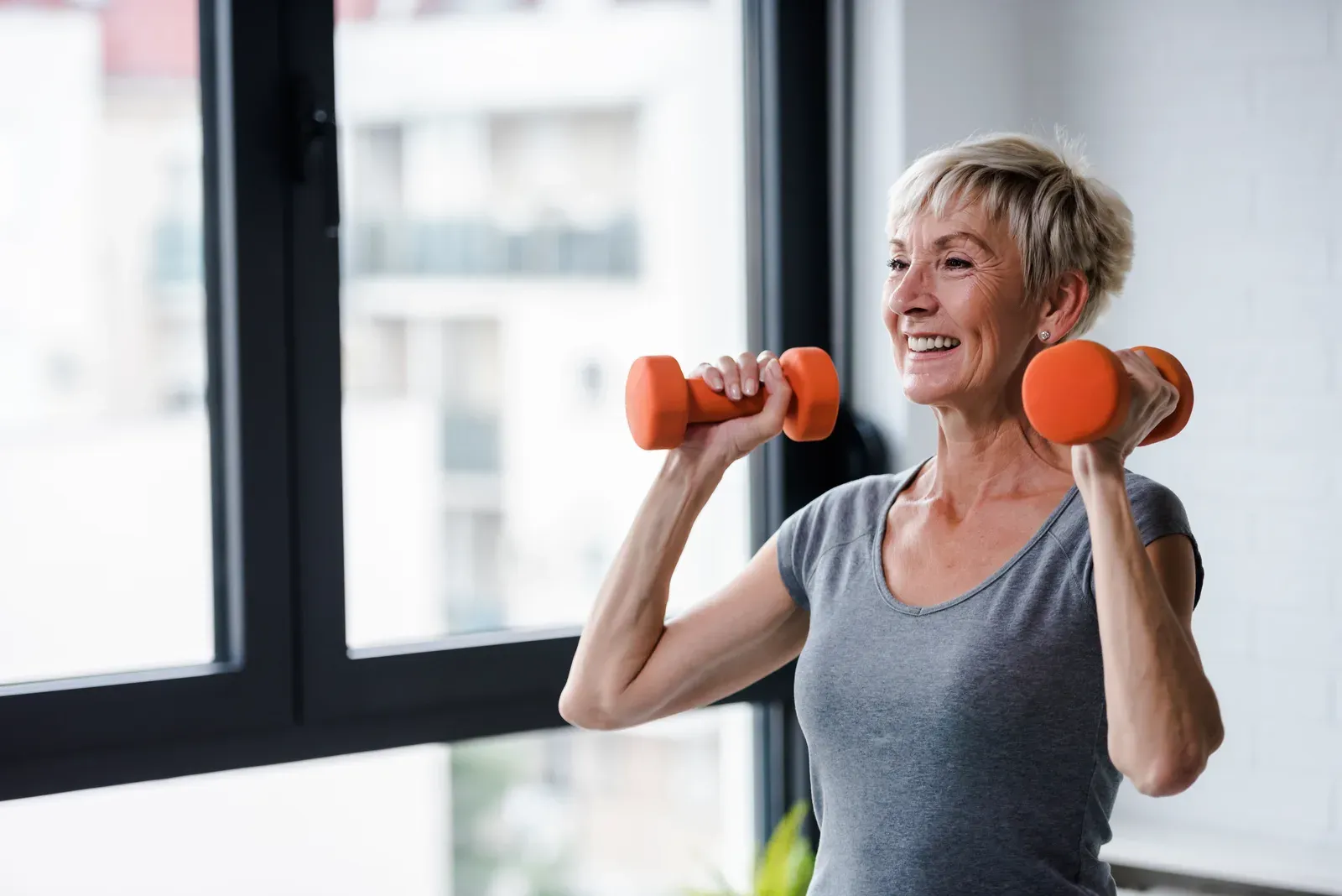 An older woman doing a seated dumbbell row as part of a supervised strength routine