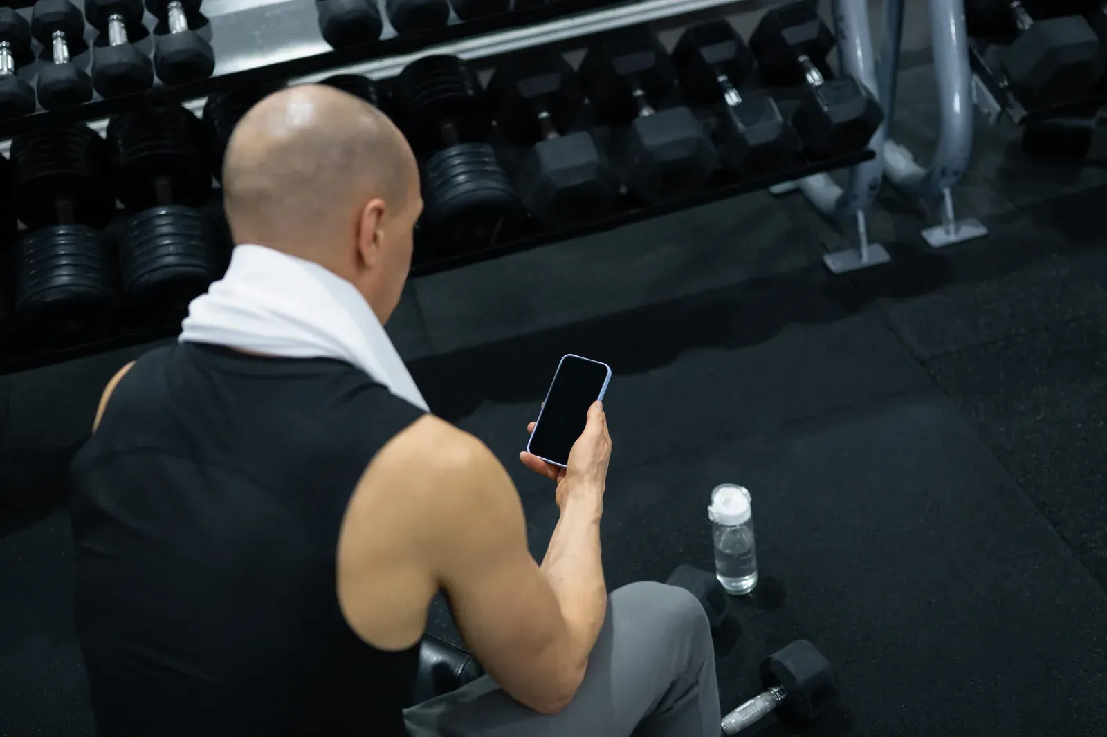 A trainer looking over an empty gym room with a notebook in hand