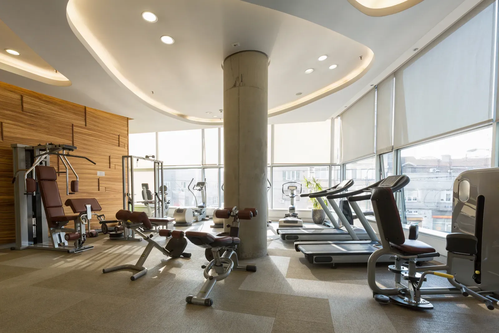 A small hotel fitness room with a treadmill and limited dumbbells