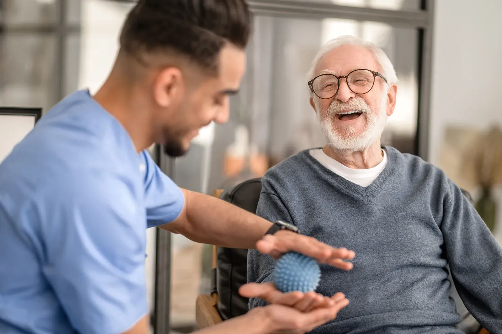 Therapist working a patient's hand with a spiky massage ball during treatment