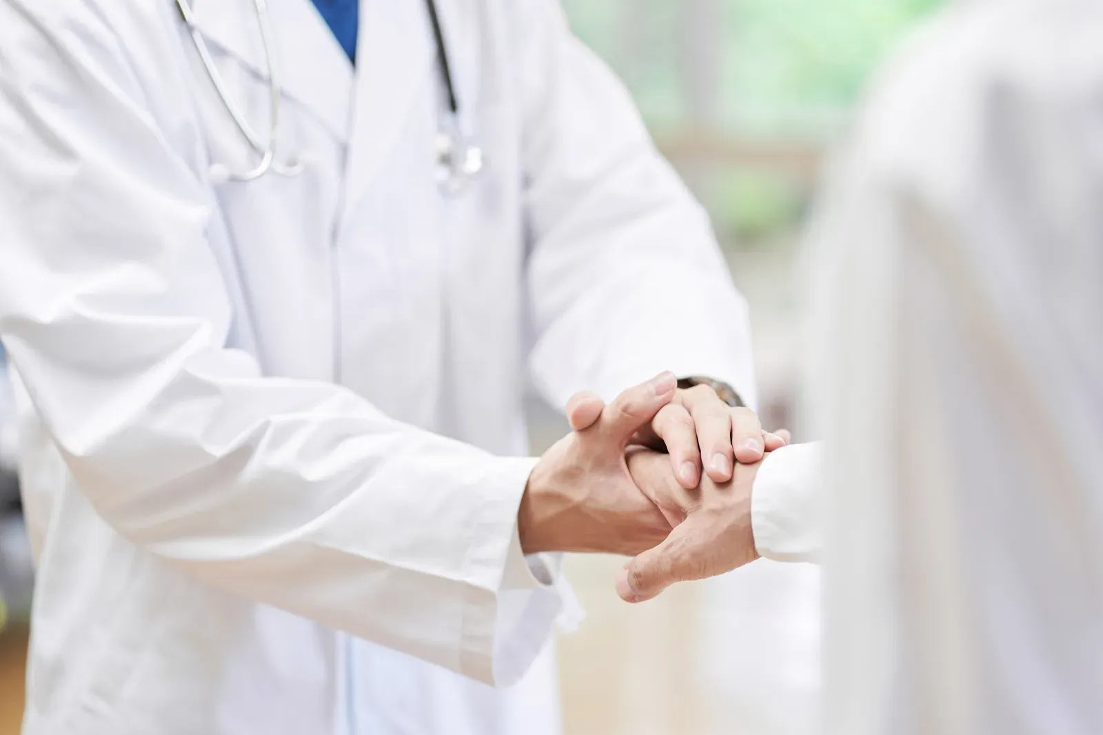 Two professionals shaking hands across a desk in a medical office