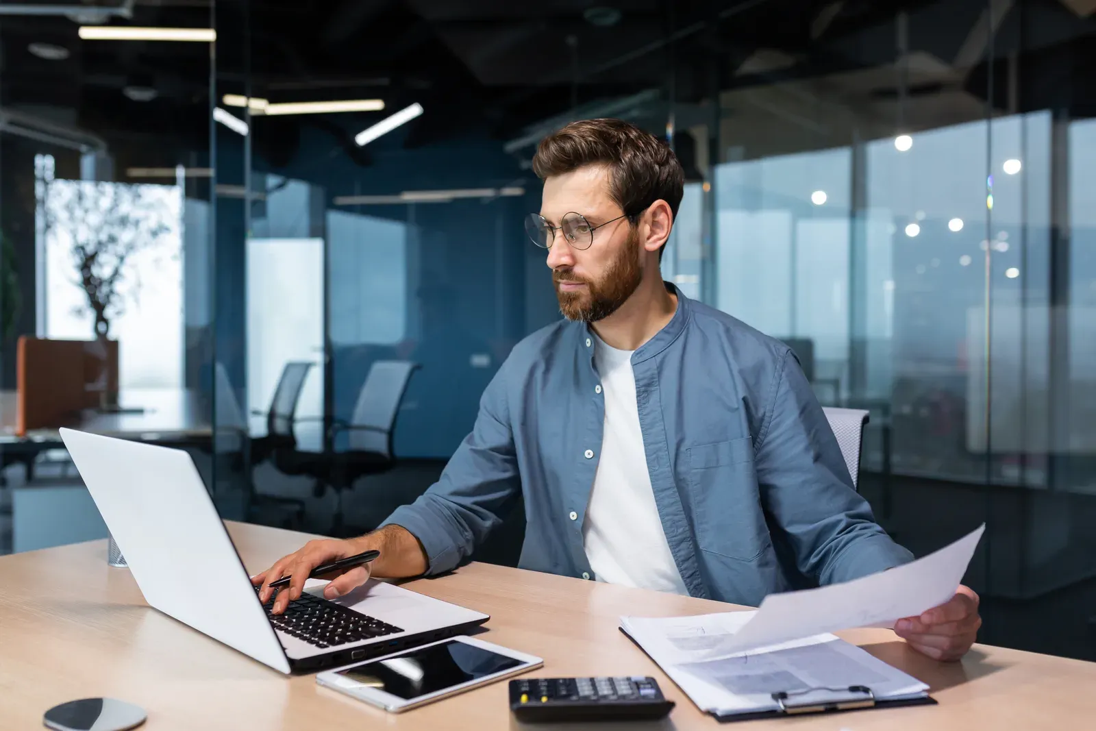 Accountant working through tax paperwork with a calculator at a desk