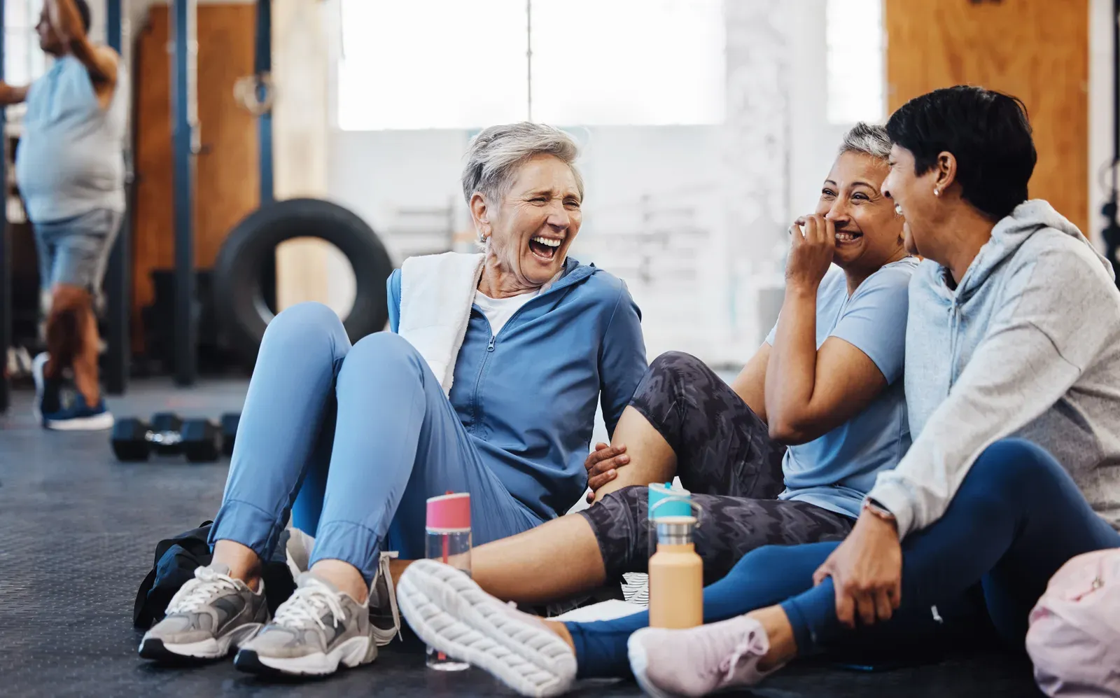 Mature women laughing together on the floor after a fitness class