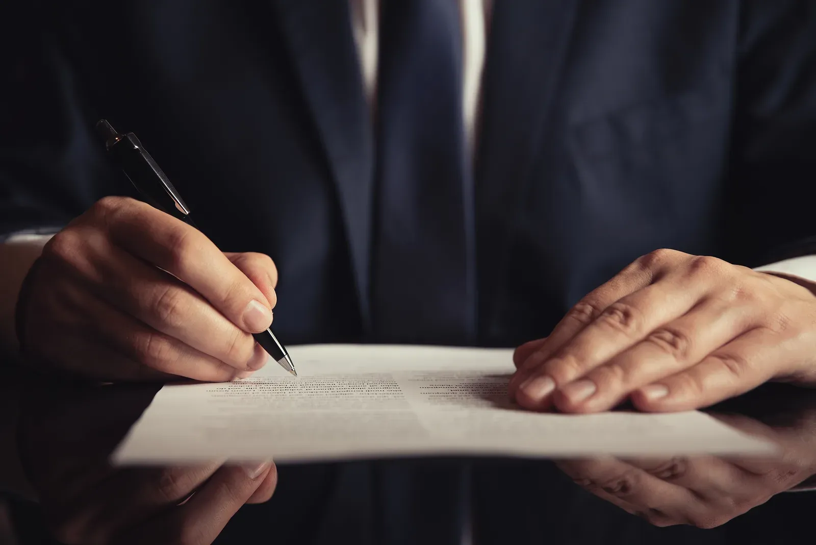 Attorney reviewing and signing legal contract paperwork at a desk