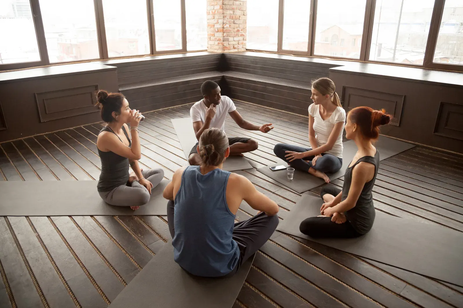 Yoga instructor talking with a group of students seated on mats