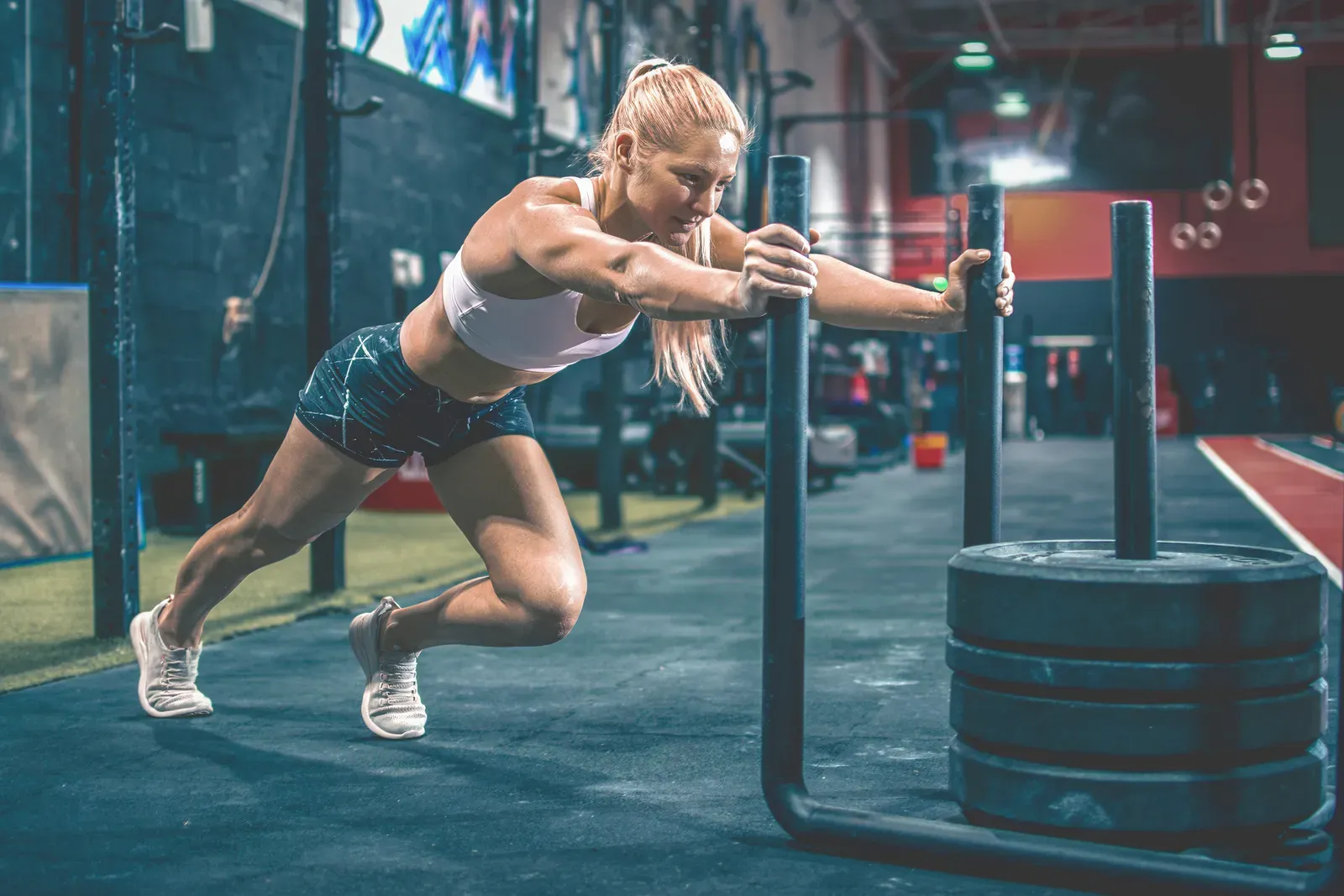 A coach observing an athlete push a weighted sled during a drill