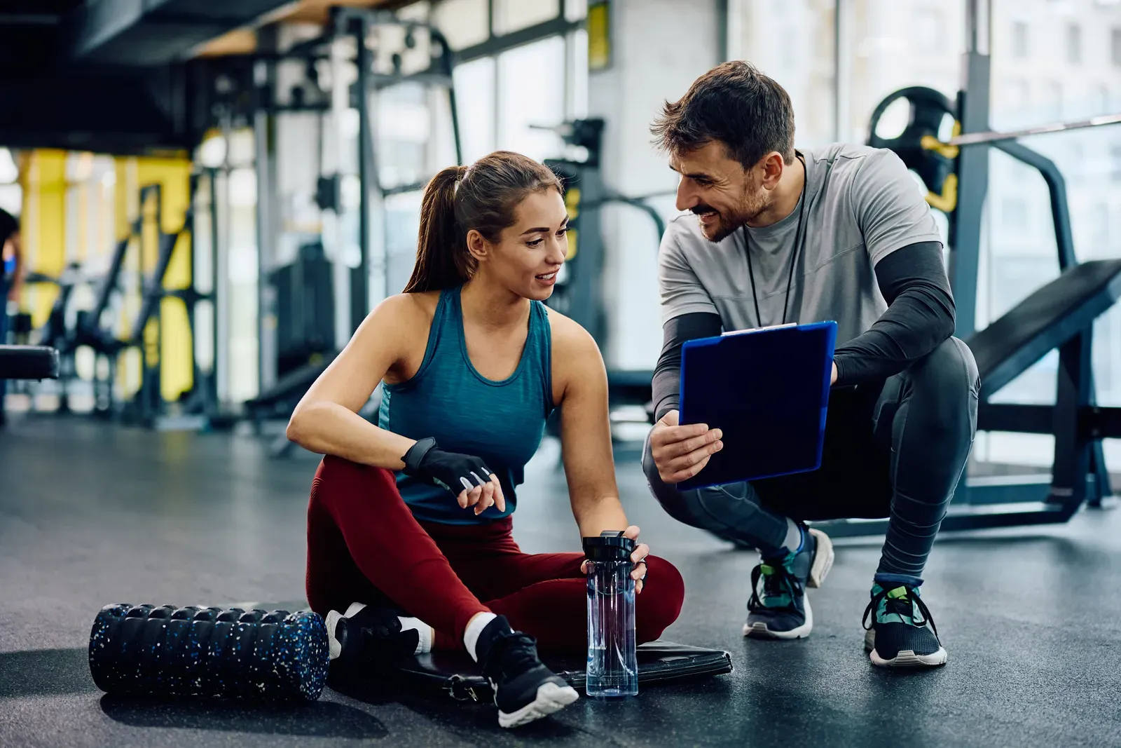 Trainer reviewing a clipboard while standing on an open commercial gym floor
