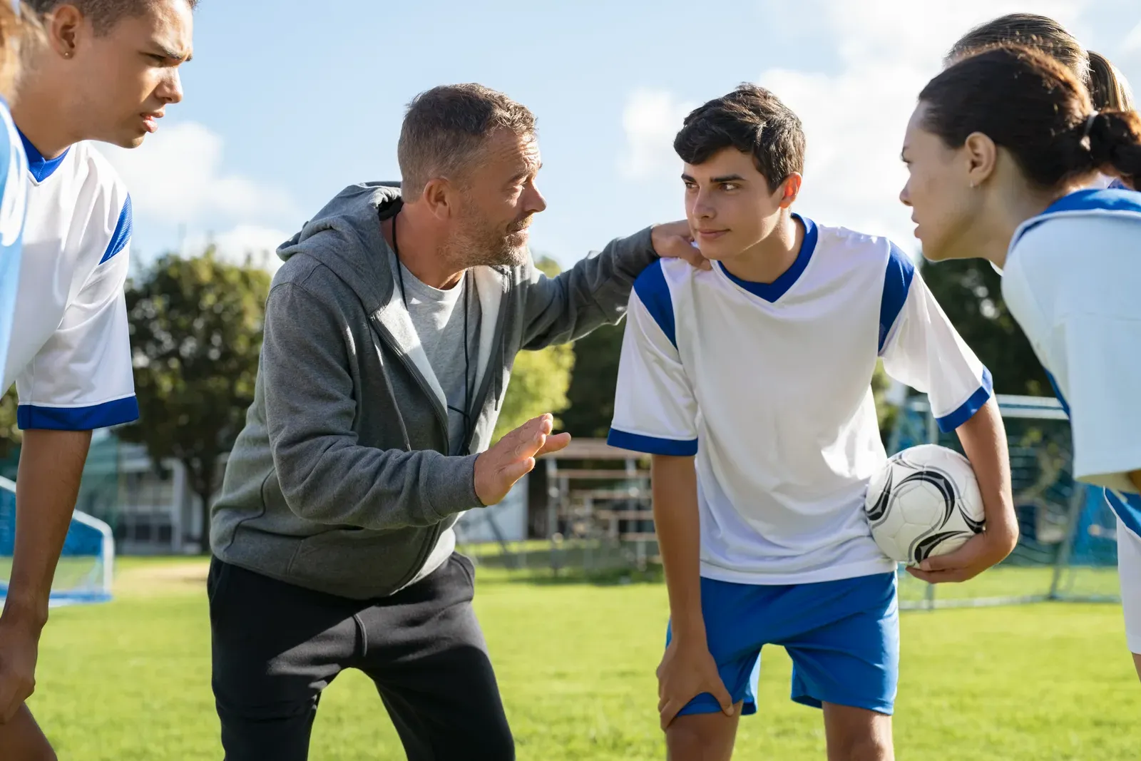 Coach in conversation with an athlete resting on a bench between sets