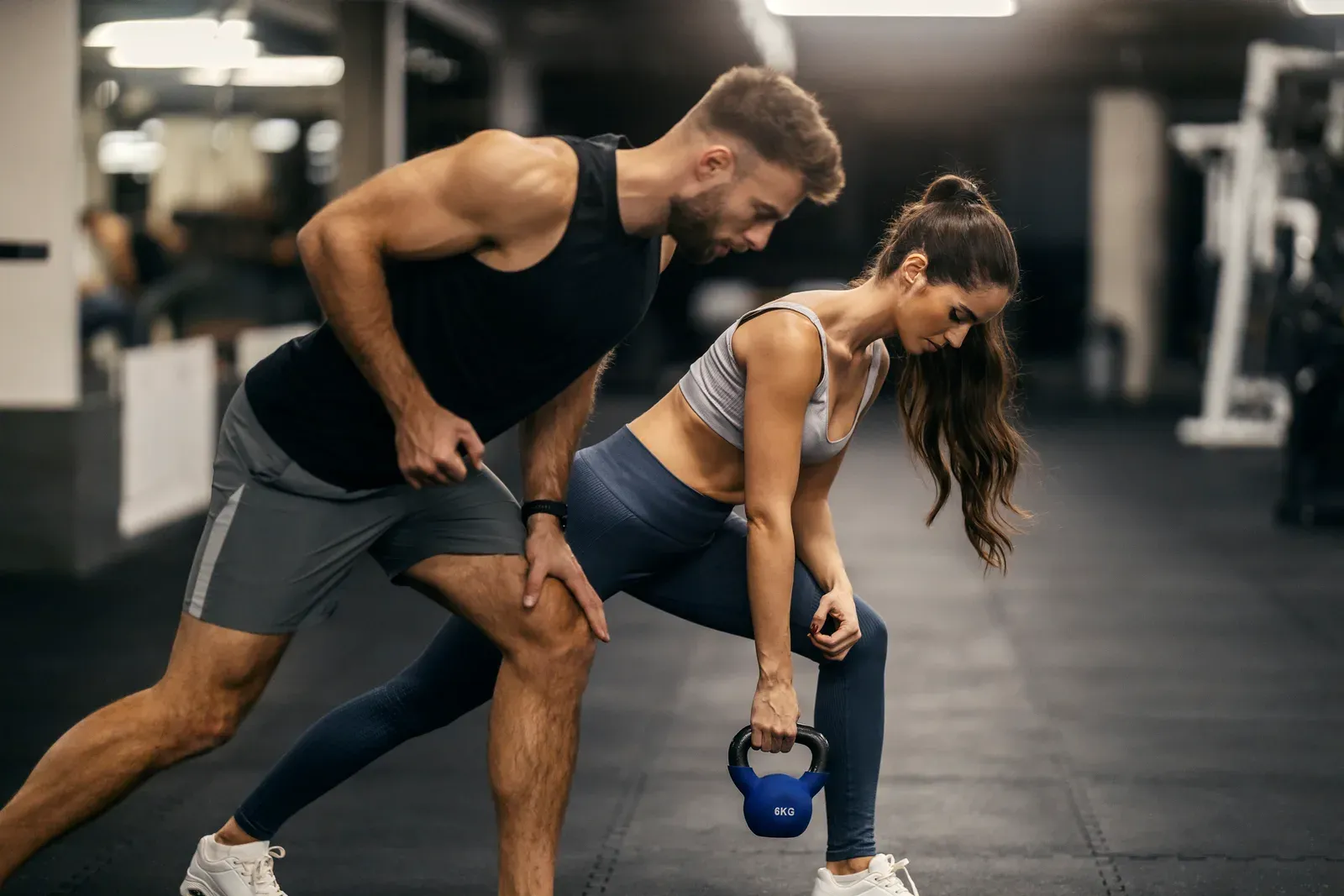 Personal trainer demonstrating kettlebell exercises to a client in the gym