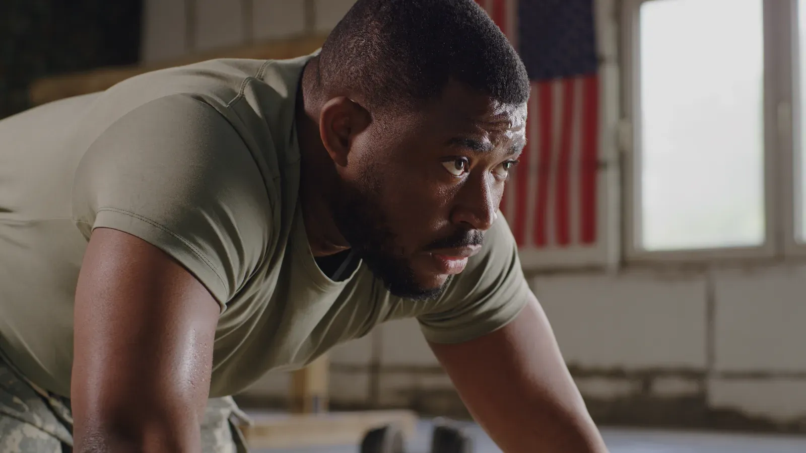 A soldier in uniform doing push-ups on a gym floor