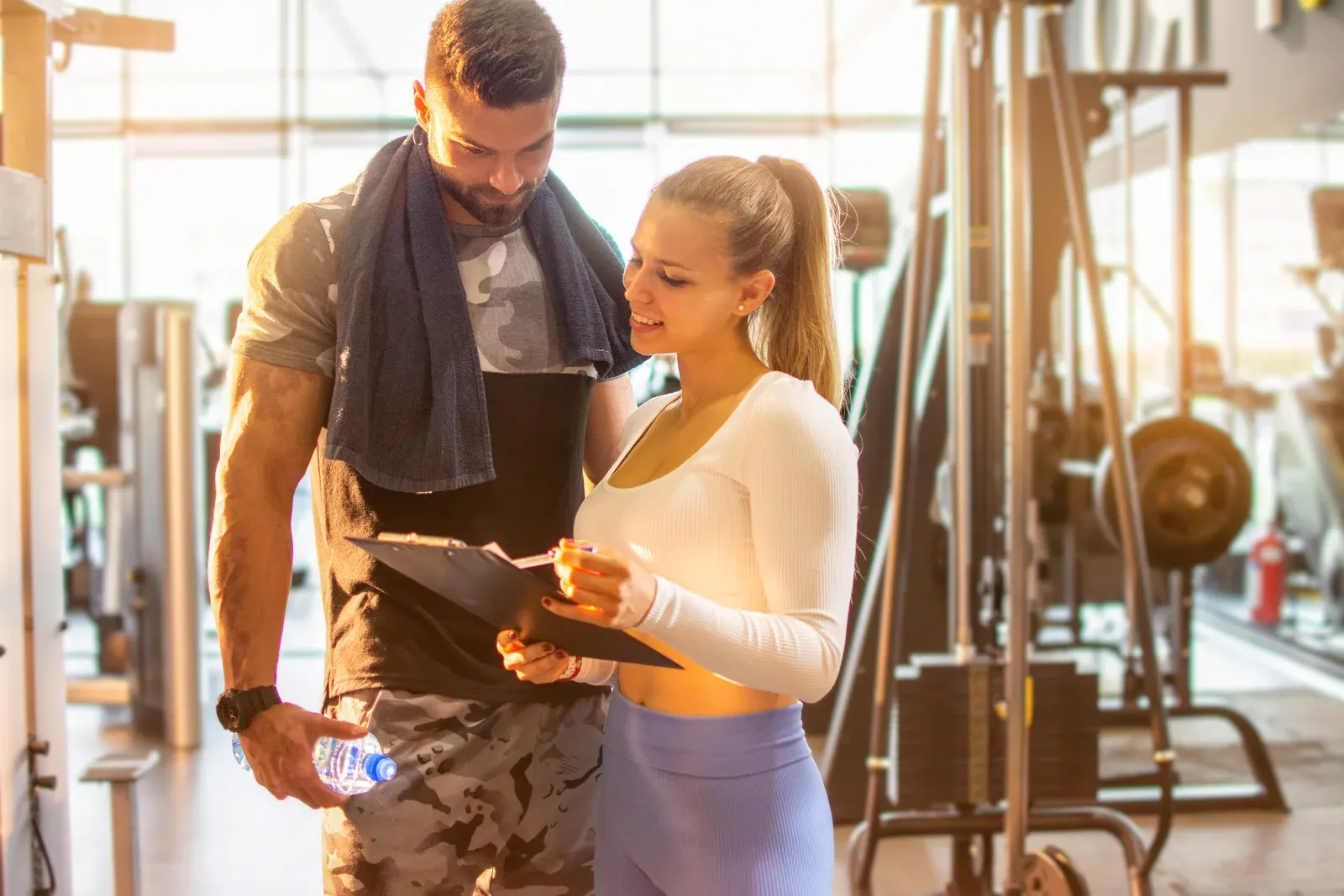 Two people in a sunlit gym reading through a training checklist together