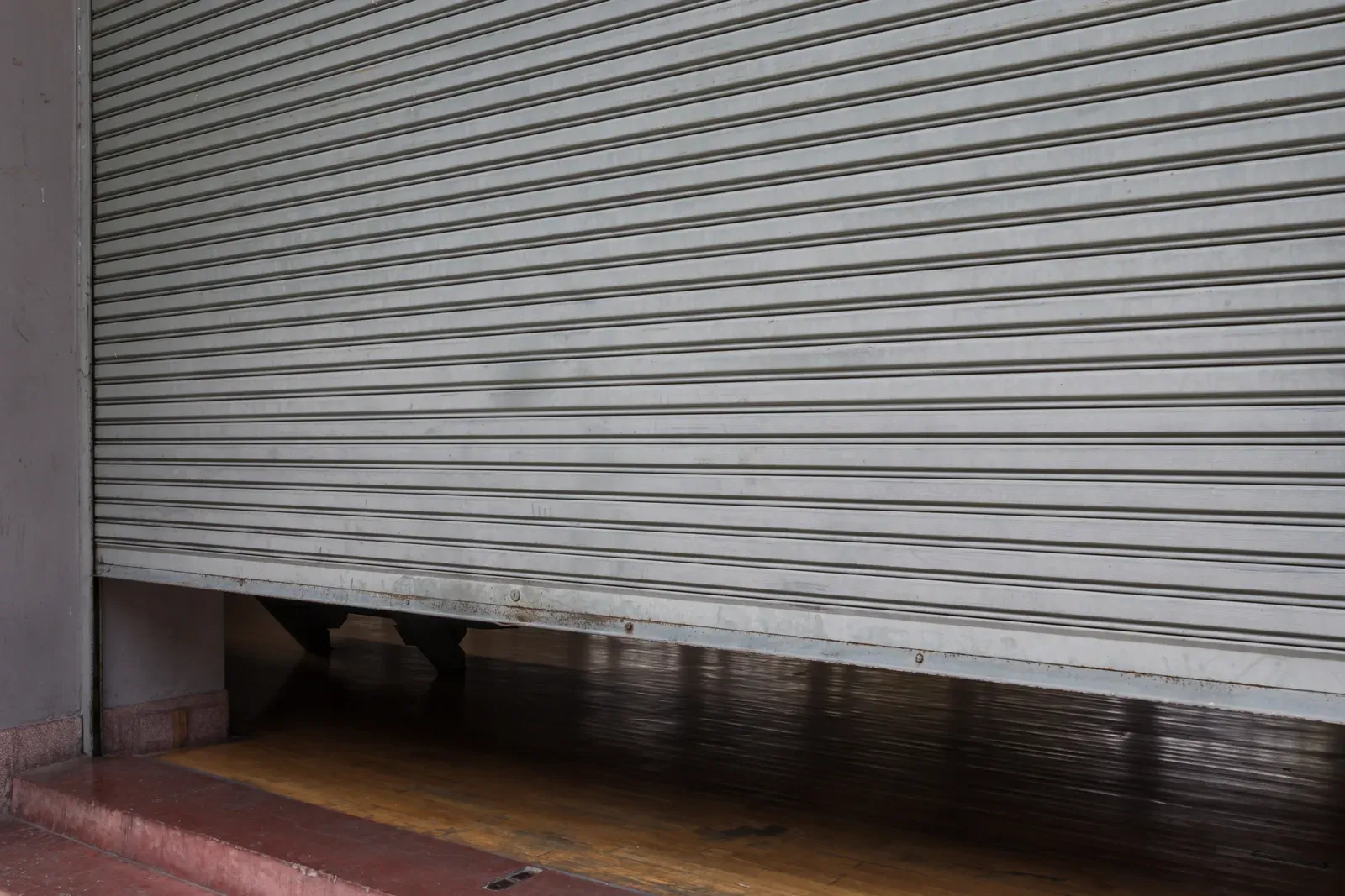 A steel roll-down shutter closed over an empty storefront